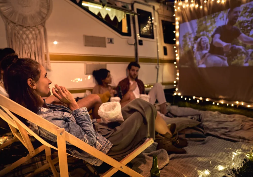 young-cheerful-people-watching-a-movie-on-camping-2023-11-27-04-51-25-utc